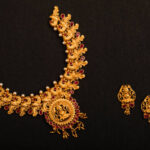 Traditional Indian Gold Necklace With Earrings on black background.