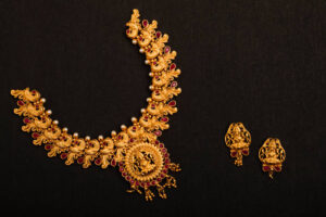 Traditional Indian Gold Necklace With Earrings on black background.